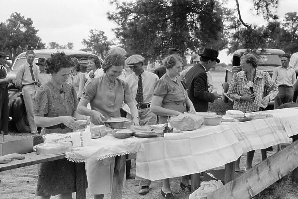 COMMUNITY DINNER, 1940. Women setting out dinner at the all day community sing in Pie Town
