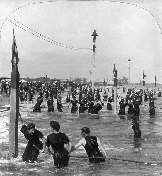 CONEY ISLAND: BEACH, c1903. Bathers holding onto ropes in the surf at Coney Island