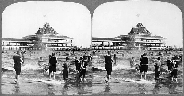 CONEY ISLAND: BEACH, c1903. Men sliding down a water toboggan in the surf at Coney Island