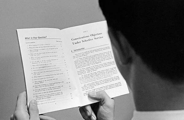 CONSCIENTIOUS OBJECTOR. A man reading a booklet on conscientious objector beliefs