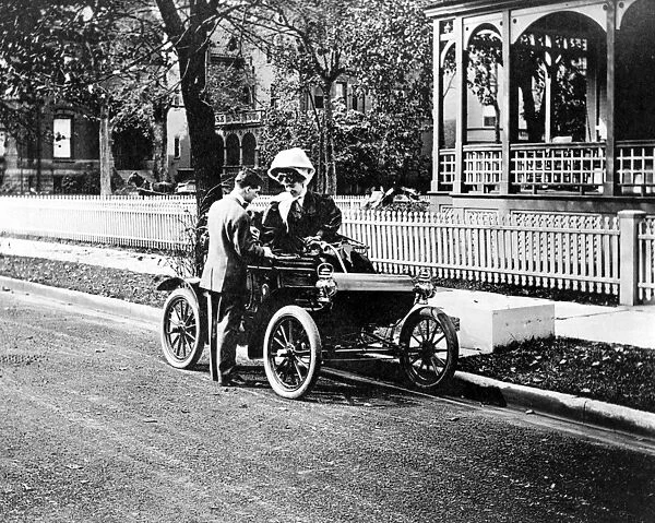 COUPLE: COURTSHIP, c1907. A woman in an automobile talking with a man on the street