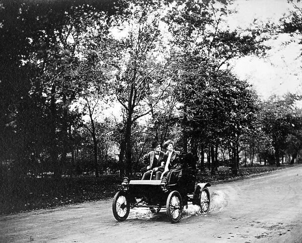 COUPLE DRIVING, c1907. A man and woman driving a car. Photograph, c1907