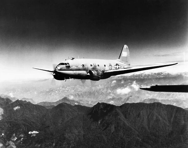 A Curtiss-Wright C-46 Commando transport aircraft flying over the Himalayas between India and China during World War II, c1944