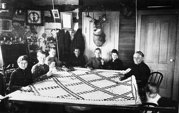DAKOTA TERRITORY: QUILTING. Pioneer women and children at a quilting party in the