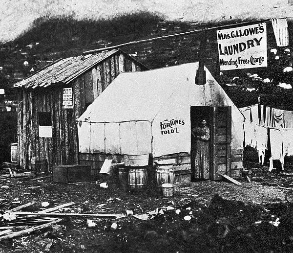 DAWSON CITY, c1900. A laundress and fortune teller in the doorway of her shop in the gold mining town of Dawson City, Yukon Territory, Canada. Photograph, c1900