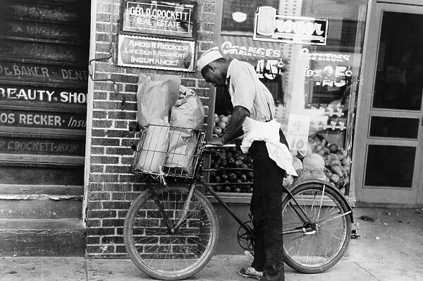 DELIVERY BOY, 1938. An African American boy delivering groceries with a bicycle in Caruthersville