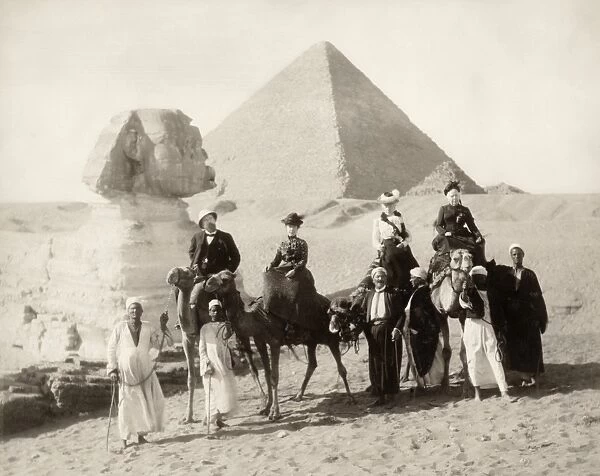 EGYPT: TOURISTS. Four tourists with local guides in front of the Great Sphinx at Giza, Egypt, with the pyramids in the background. Photograph, late 19th century