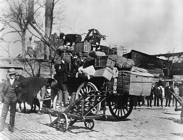 ELLIS ISLAND, c1910. Men loading immigrants baggage on to a wagon at Ellis Island