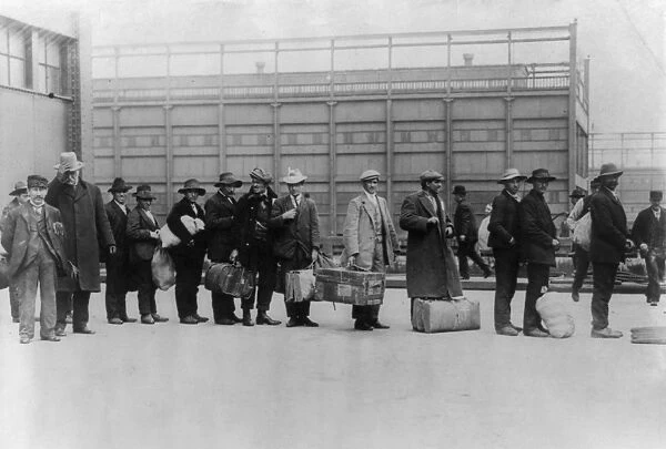 ELLIS ISLAND, c1911. Immigrant men arriving at Ellis Island with their belongings