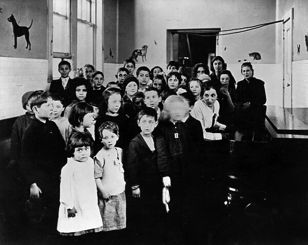 ELLIS ISLAND, c1915. A group of immigrant children learning American songs in a