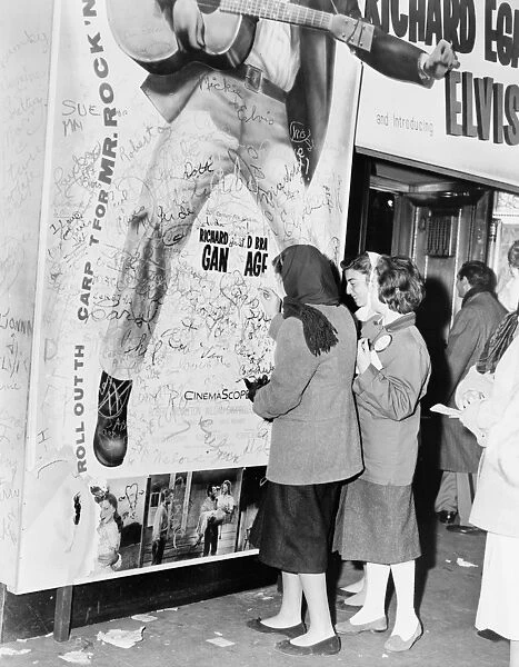ELVIS FANS, 1956. Teenage girls adding graffiti to the Love Me Tender movie poster