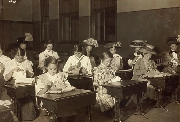 EMBROIDERY CLASS, 1909. Working girls learning embroidery in a free evening class