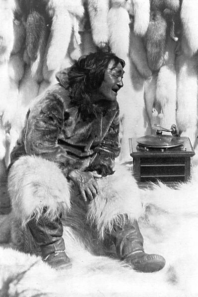 ESKIMO AND PHONOGRAPH. An Eskimo man sitting among furs listening to the phonograph