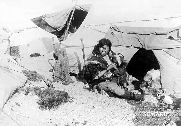 ESKIMO WOMAN AND CHILD. An Eskimo woman sitting outside a tent breast-feeding her baby, Alaska