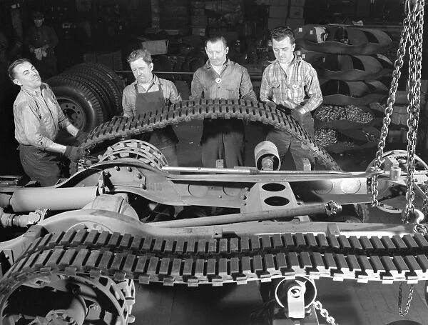 Factory crew at the White Motor Company in Cleveland, Ohio, mounting a tractor belt on a half-track military vehicle for the U. S. Army during World War II. Photograph by Alfred Palmer, December 1941