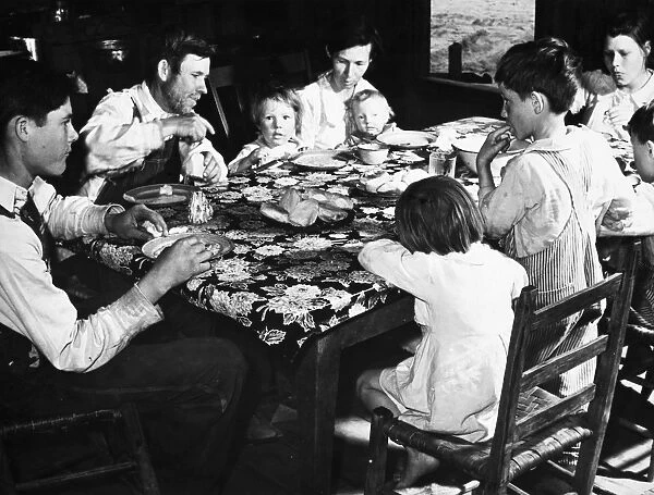 FAMILY DINING, 1939. A new rehabilitation family dining on biscuits, bread