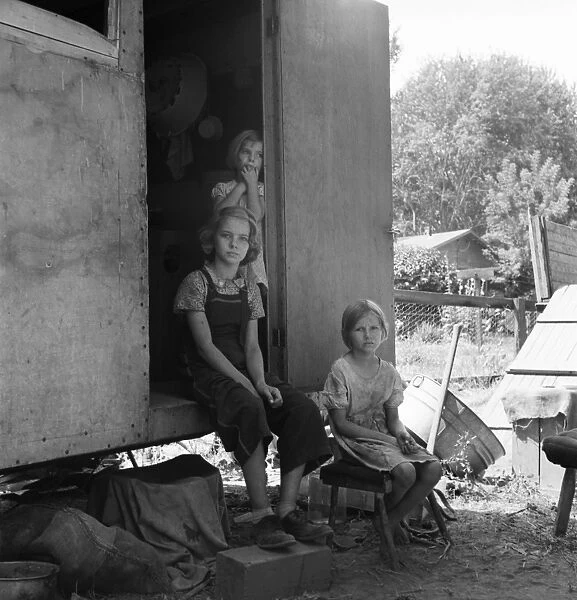 FARM FAMILY, 1939. The oldest girl seated in the doorway of the house trailer cares