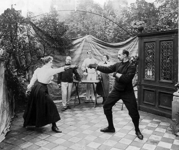 FENCING, c1904. A woman and a man dueling as three people watch. Photograph, c1904