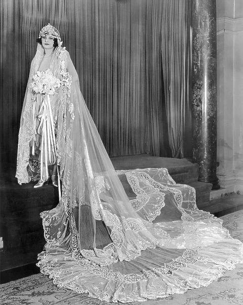 FILM: MELODY GIRL, 1937. Peggy Shaw, Pathes Melody Girl, poses in a $10, 000 gown of silver cloth with flounces of net and train of Duchess Lace, adorned with silver flowers and buds
