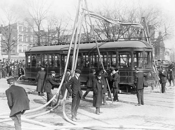 FIREMEN, c1918. Firemen with hoses over a street car, United States. Photograph, c1918
