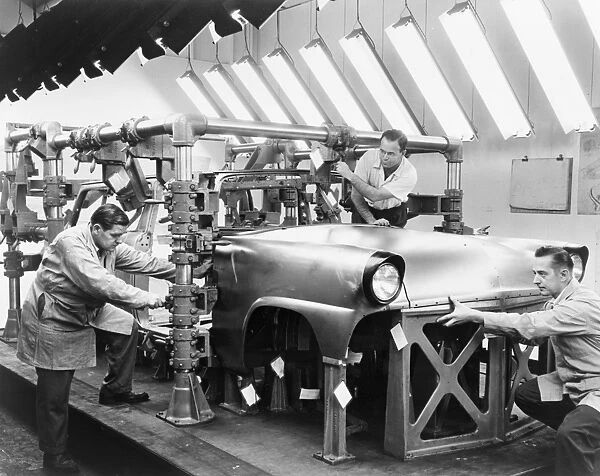 FORD ASSEMBLY LINE, 1954. Three men at work on an automobile on a Ford assembly line