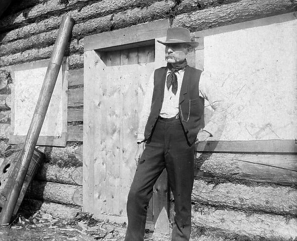 GOLD MINER, c1897. A gold miner standing outside of a log cabin in the Yukon Territory