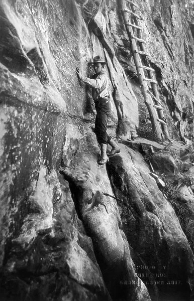 GRAND CANYON: CLIMBER. Photographer Ellsworth Kolb scaling a wall of rock 400 feet above the mine on the Hummingbird Trail in the Grand Canyon in Arizona; at upper right is a ladder leading to a cliff dwelling. Photographed c1913