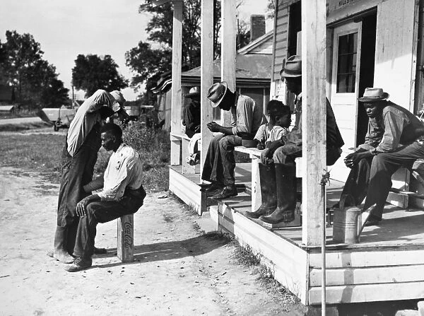 HAIRCUTTING, 1939. Young men cutting each others hair in front of Mileston Plantation