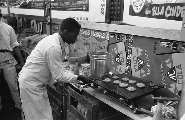 HAMBURGER GRILL, 1938. A cook making hamburgers in a concession stand at the National