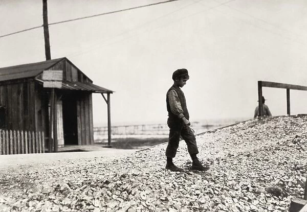 HINE: CHILD LABOR, 1911. A young oyster shucker standing on mound of shells in Biloxi