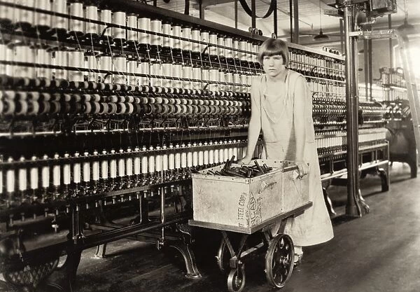HINE: CHILD LABOR, 1924. A young worker pushing a cart of machine parts at the
