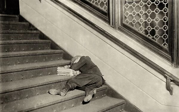HINE: NEWSBOY, 1912. Newsboy sleeping on the stairs with newspapers at night in Jersey City