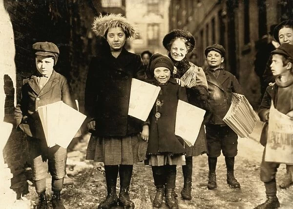 HINE: NEWSBOYS, 1909. Newsboys and newsgirls coming through the alley carrying