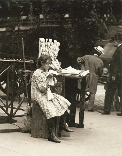 HINE: NEWSGIRL, 1910. A young newsgirl seated on a crate while tending to the newspaper