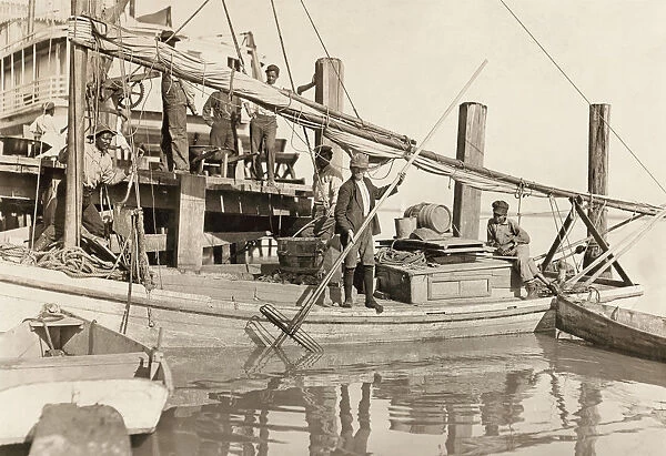 HINE: OYSTER FISHING, 1909. Men and two boys aboard an oyster fishing boat in Apalachicola