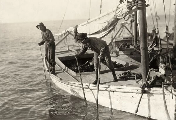 HINE: OYSTER FISHING, 1911. Two young oyster fisherman aboard an oyster boat in Mobile Bay