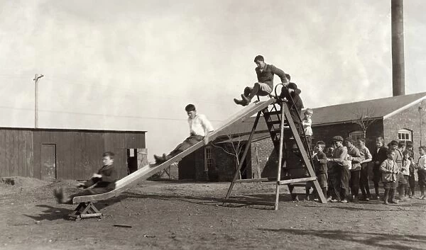 HINE: SCHOOLYARD, 1917. Children playing on the slide in the schoolyard of the