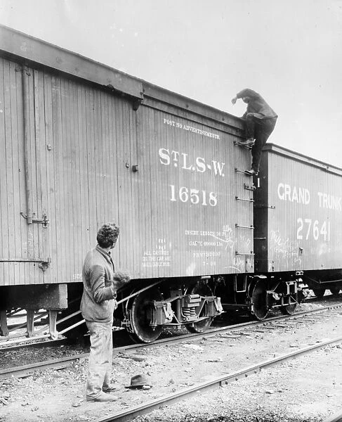 HOBOS, c1915. A hobo climbing on top of a railroad car. Photograph, c1915