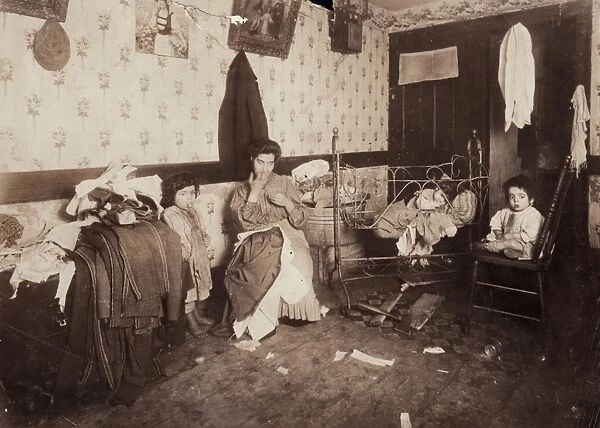 HOME INDUSTRY, 1912. A woman in a tenement in New Yorks Lower East Side, sewing mens trousers