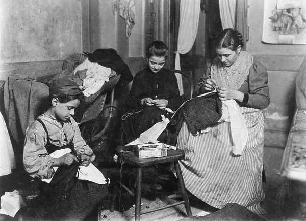 HOME INDUSTRY, c1910. An immigrant family making mens trousers in their New York