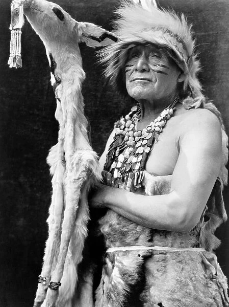 HUPA DANCER, c1923. A Hupa Native American of California, dressed in a white deerskin ceremonial dance costume. Photograph by Edward Curtis, c1923