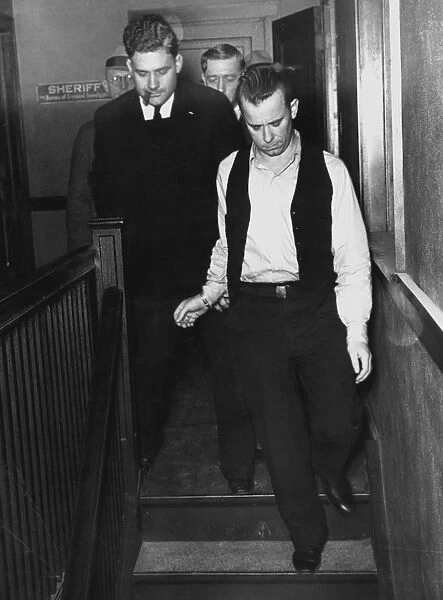 JOHN DILLINGER (1903-1934). American bank robber, 1934. Dillinger (wearing open vest) being led from jail to a courtroom at Crown Point, Indiana, on 9 February 1934, for arraignment on the charge of killing a policeman in East Chicago, Indiana