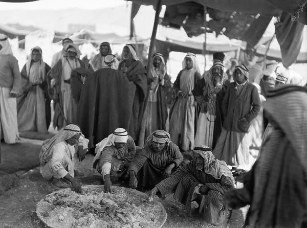 JORDAN: GATHERING, c1936. A group of Bedouins gather for a meal around a large pot of food