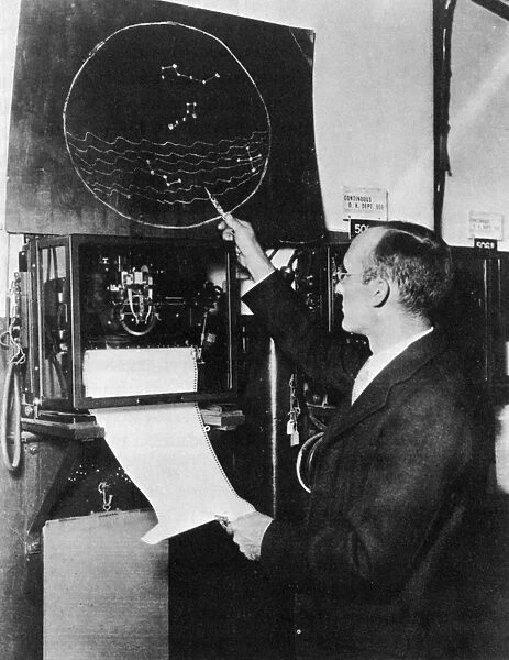 KARL GUTHE JANSKY (1905-1950). American physicist and radio engineer. Pointing to a chart, 1933, indicating the area of the Milky Way galaxy where he first detected radio noises from space