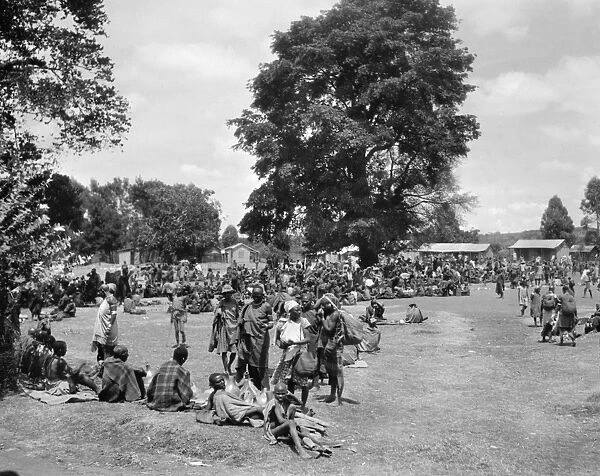 KENYA: MARKETPLACE, 1936. A crowd gathered in a marketplace beneath a large tree in Karatina