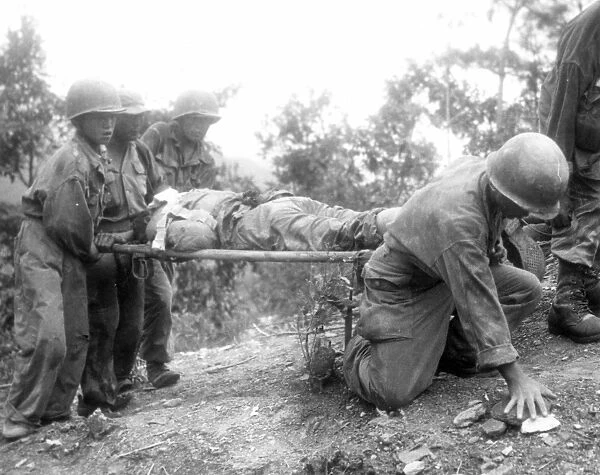 KOREAN WAR, 1952. Western Front: Battle-weary allied soldiers carry their wounded after heavy fighting with Communist forces at Old Baldy Mountain, which was recaptured by the allied troops, August 1952