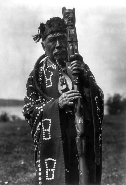 KWAKIUTL CHIEF, c1914. A portrait of Hamasaka, a Kwakiutl chief, wearing a blanket ornamented with buttons, holding a ceremonial staff and a shamans rattle. Photographed by Edward S. Curtis, c1914