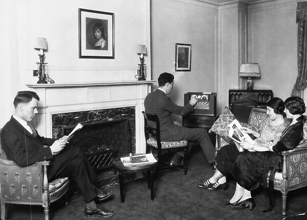 LIVING ROOM, c1927. Scene in an American living room, with one man tuning the radio