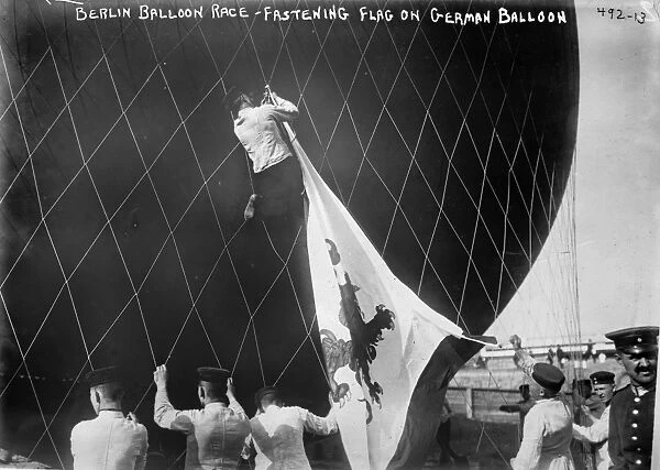 A man attaching a German flag to a hot air balloon before a race in Berlin, Germany. Photograph, 1908