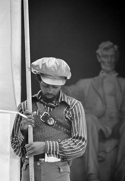 A man holding a banner on the steps of the Lincoln Memorial while attending a Black Panther convention in Washington, D. C. 19 June 1970. Photographed by Warren K. Leffler or Thomas J. O Halloran